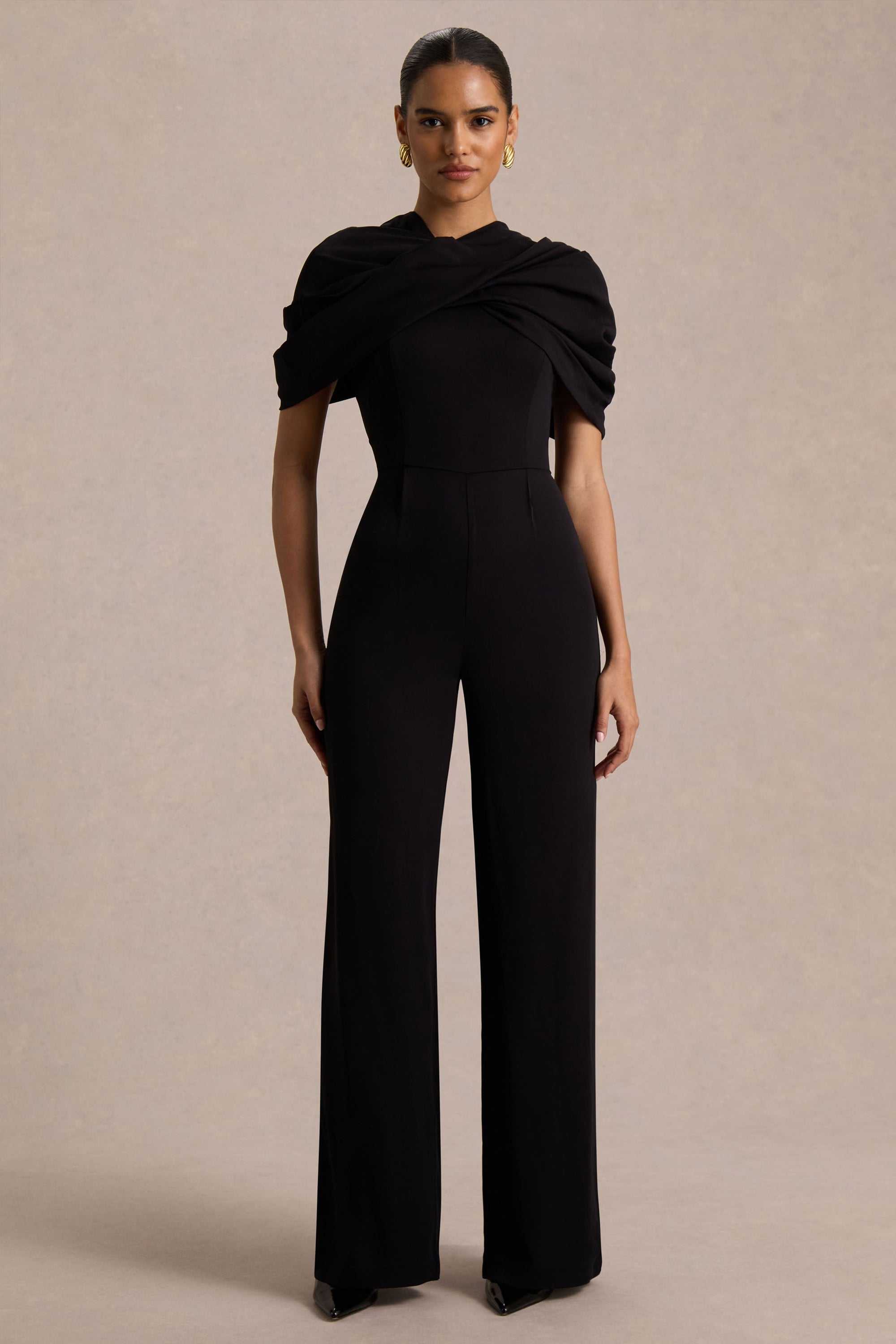 Raquel | Svart byxdress med asymmetrisk halsringning och tvinnad capeärm
