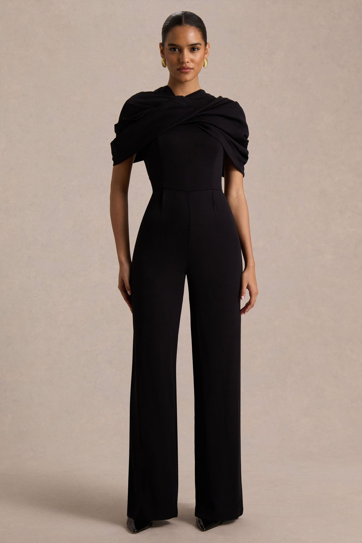 Raquel | Svart byxdress med asymmetrisk halsringning och tvinnad capeärm