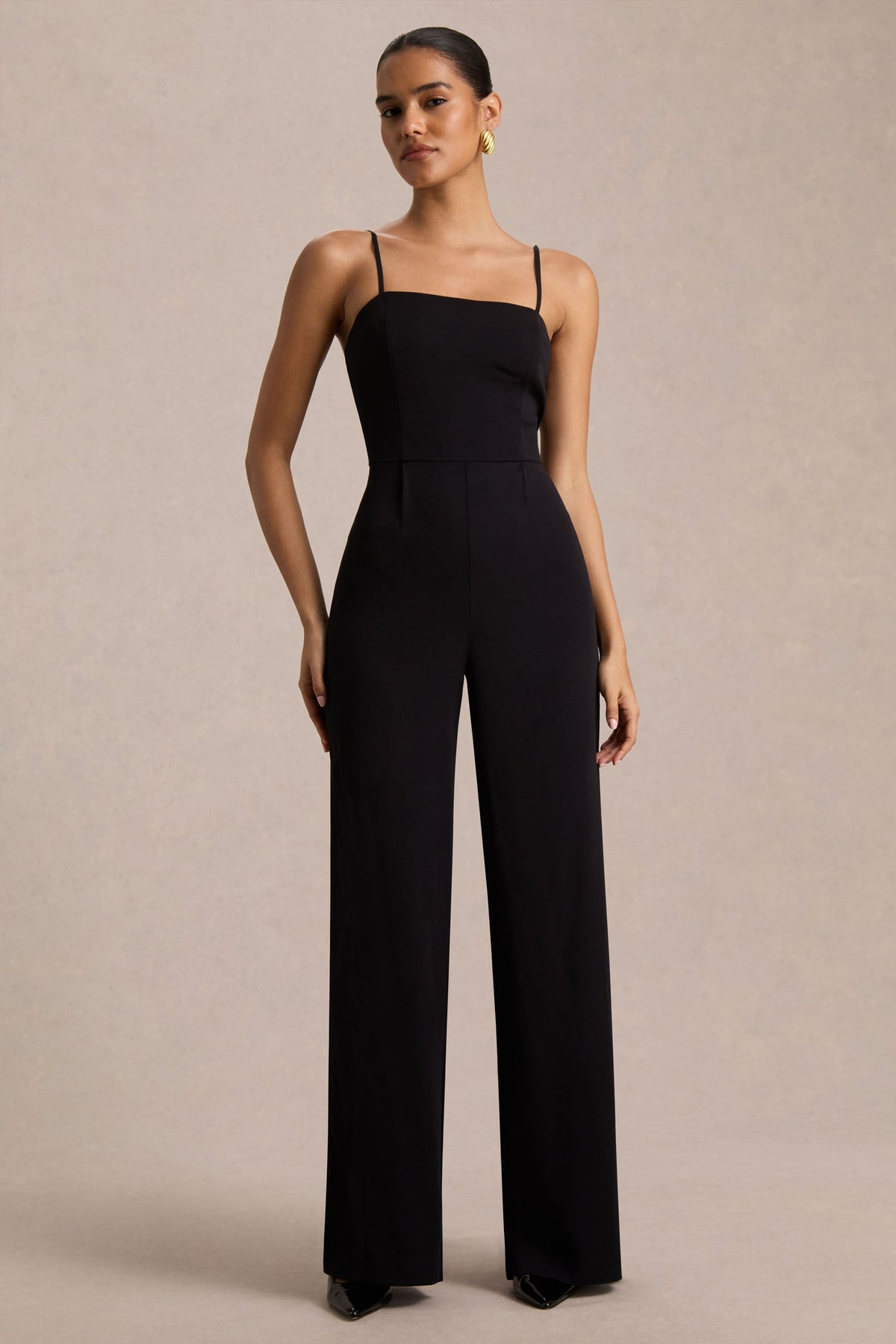 Raquel | Svart byxdress med asymmetrisk halsringning och tvinnad capeärm