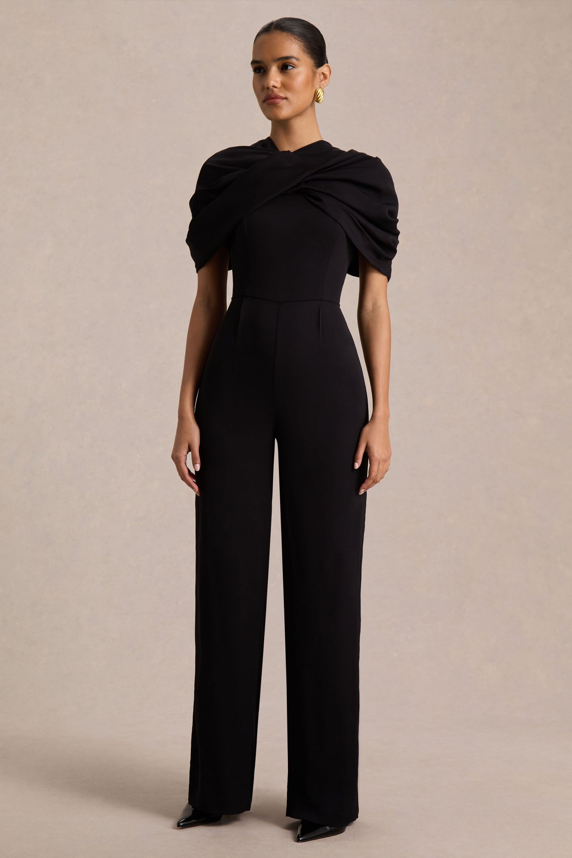 Raquel | Svart byxdress med asymmetrisk halsringning och tvinnad capeärm