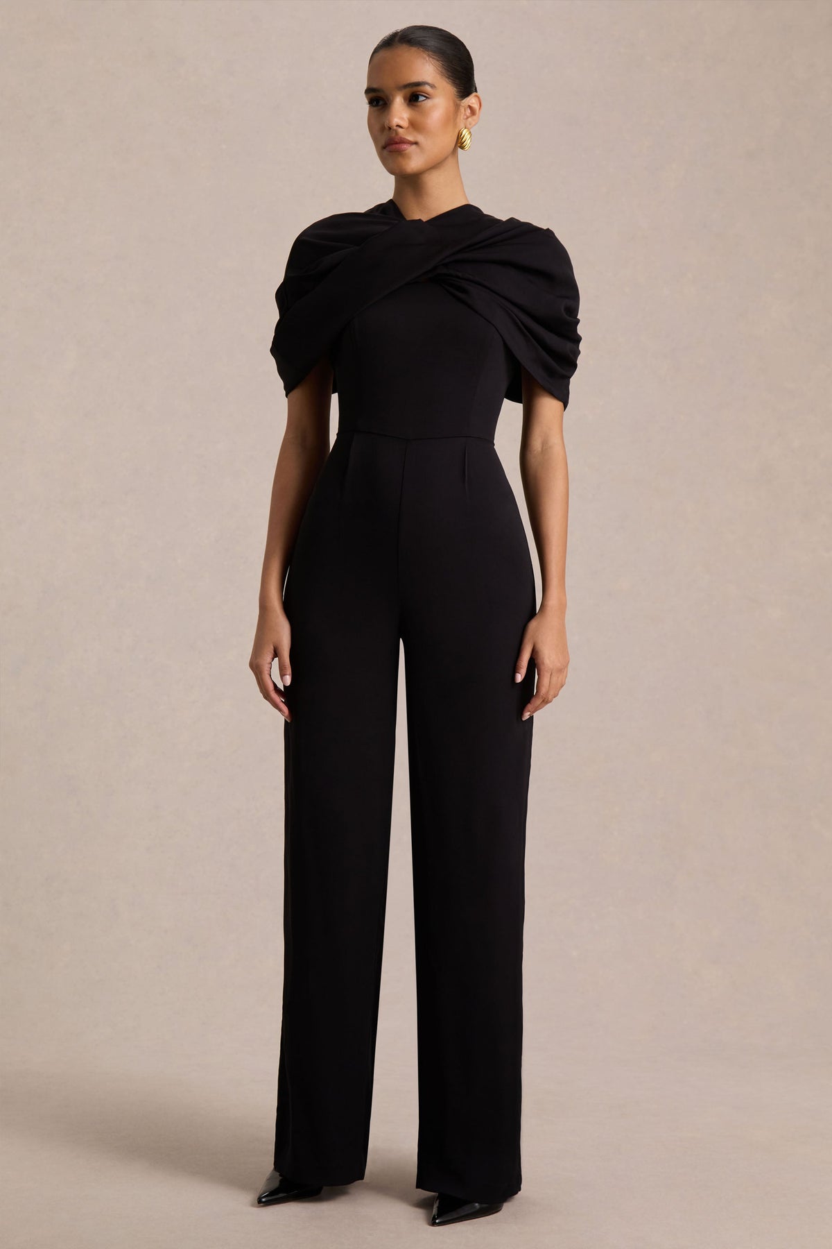 Raquel | Svart byxdress med asymmetrisk halsringning och tvinnad capeärm