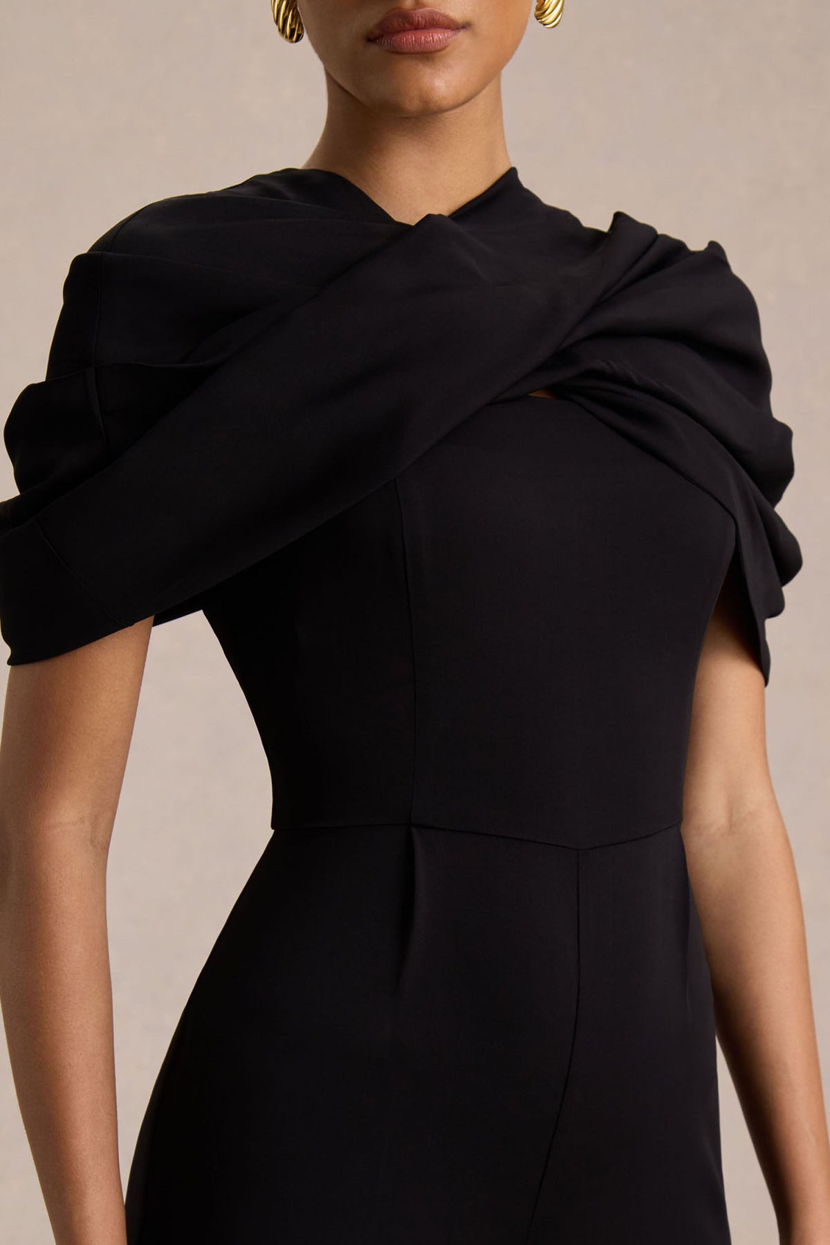 Raquel | Svart byxdress med asymmetrisk halsringning och tvinnad capeärm
